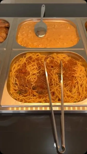 Cuba de espaguete à bolonhesa com pegador, ao lado de uma cuba de frango ao molho